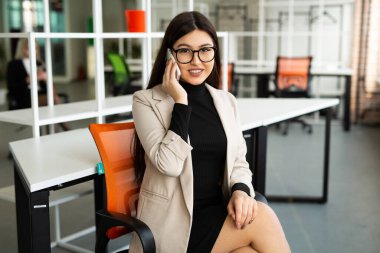 Ofiste cep telefonlu, gözlüklü güzel bir kadın var. 