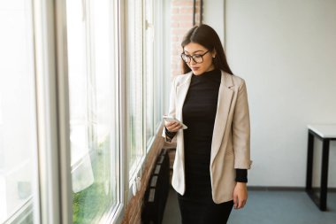 Ofiste cep telefonlu, gözlüklü güzel bir kadın var. 