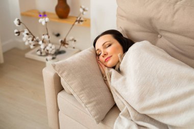 güzel genç bir kadın kanepede uyuyor battaniyenin altında 