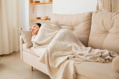 güzel genç bir kadın kanepede uyuyor battaniyenin altında 