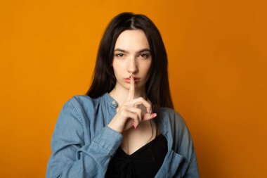 Sarı arka planda el hareketleriyle güzel bir kadının portresi.