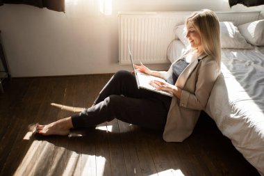 Evde dizüstü bilgisayarı olan genç ve güzel bir bayan çalışıyor.