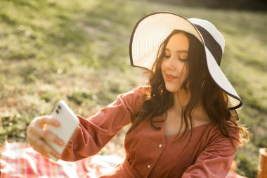 Şapkalı, cep telefonlu güzel bir kadının portresi.