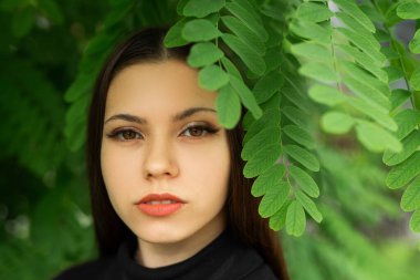 Yeşil yaprakların yanında güzel bir kadın makyajı olan nazik bir görüntü.