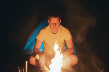 Gece kamp ateşinin yanındaki turist..