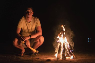 Gece kamp ateşinin yanındaki turist..