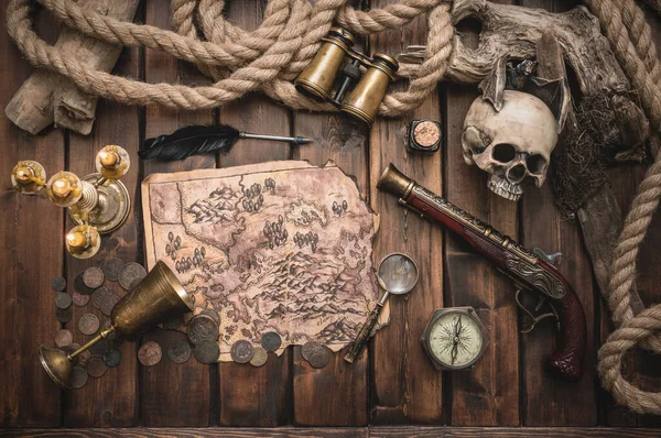 Pirate treasure map and other accessories on the brown wooden table concept background.