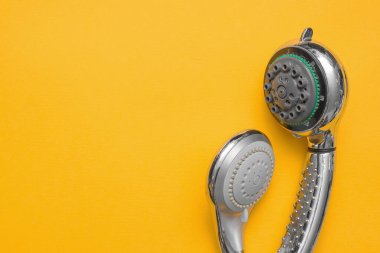 Sarı düz arka planda iki farklı duş başlığı ve fotokopi alanı var. Duş başlığının değiştirilmesi.