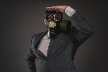 Gaz maskeli adam karanlık arka planda ileriye bakıyor..