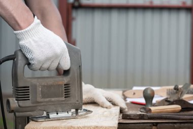 Marangoz tezgahtaki yapbozun yanında bir odun kesiyor. Yakından..
