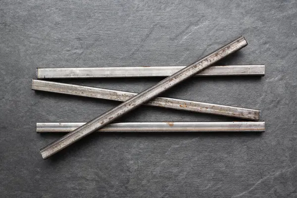 Siyah düz arkaplandaki siyah metal profil tüpleri.