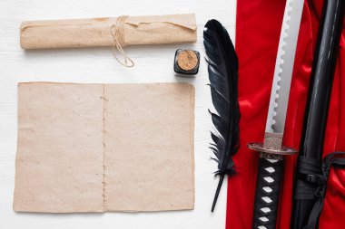 Katana sword, blank page book with copy space and ancient paper scroll on the white wooden table background. Book of fighting techniques concept. clipart