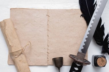 Katana kılıcı, beyaz tahta masa zemininde kopya alanı ve antik kağıt parşömeni olan boş bir sayfa kitabı. Dövüş teknikleri kitabı konsepti.