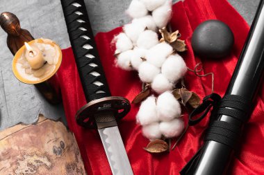 Katana kılıcı, kağıt kaydırma ve yanan mum fotokopi alanı ile siyah masa zemininde.