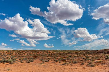 Çöl manzarası ve kabarık bulutlu mavi gökyüzü.