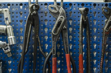 Mekanik atölyedeki mavi rafta asılı duran araçlar