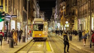 Milano caddesinde geceleri tramvaylar ve etrafta yürüyen insanlar...