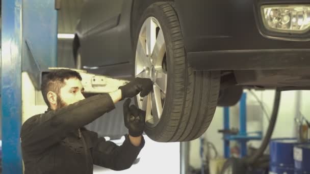 Mecánico realiza cambio de neumáticos en el coche — Vídeo de stock