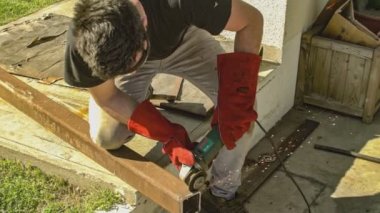 Açı öğütücüsü olan işçiler inşaat sahasında demir profili kesiyor