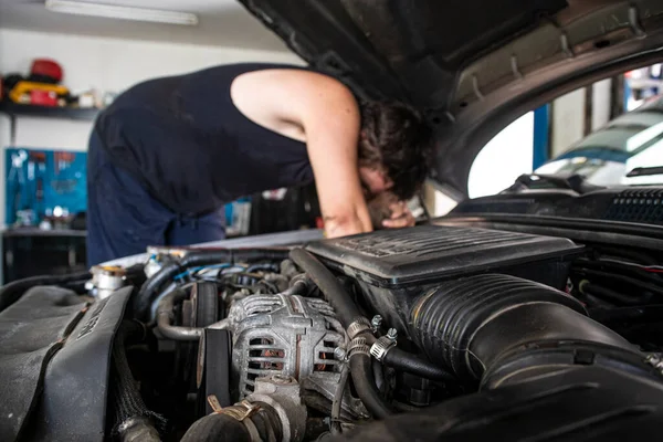 Mechanic at work on the car engine in a workshop