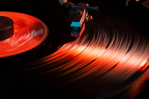 Needle detail on vinyl record on turntable, low light image with reflection