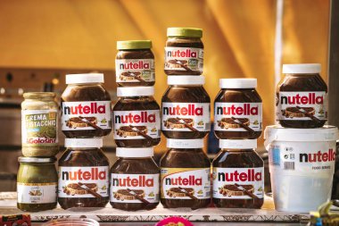 Rome, italy 10 september 2025: multiple jars of nutella chocolate hazelnut spread and pistachio cream on display, showing food products available for sale