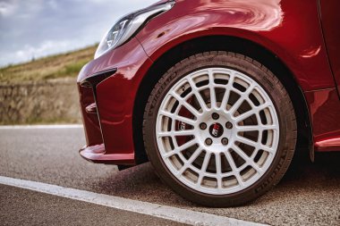 Rome, italy 10 september 2025: red toyota gr yaris front rally wheel closeup with white rim and tire on asphalt road, sporty hot hatch detail in daylight