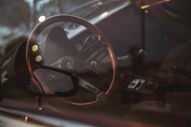 Rome, italy 10 september 2025: interior of a classic alfa romeo car, featuring a wooden steering wheel and dashboard, seen through a subtly reflective window