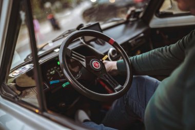 Rome, italy 10 september 2025: man at wheel of vintage fiat, close-up of dashboard and steering wheel capturing classic analog instruments and retro driving vibe