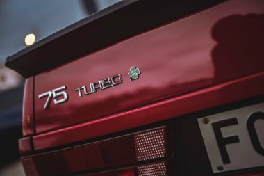 Rome, italy 10 september 2025: rear view of red alfa romeo 75 turbo showing iconic quadrifoglio cloverleaf badge and sporty rear spoiler, classic italian performance car