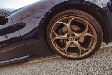 Rome, italy 10 september 2025: alfa romeo veloce in dark blue showcasing shiny gold multi-spoke alloy wheel with brand logo and sporty elegant design