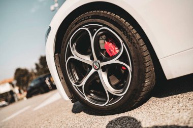 Rome, italy 10 september 2025: alfa romeo giulia white car wheel with elegant alloy rim and red brake caliper, close-up detail on sunny asphalt driveway