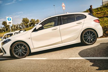 Rome, italy 10 september 2025: white bmw 1 series hatchback parked on road, showcasing modern automotive design and urban mobility during sunny weather