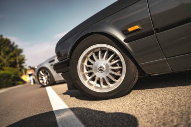 Rome, italy 10 september 2025: bmw e30 displaying vintage styling with its classic wheel, rim, and tire on an asphalt road experiencing strong sunlight