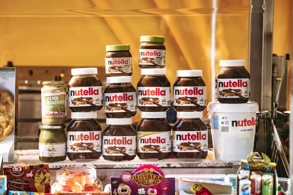 Rome, italy 10 september 2025: nutella jars and a large food-service bucket stacked on a market stall, showcasing creamy chocolate-hazelnut spread abundance