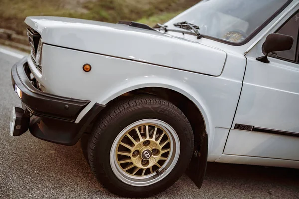 Rome, italy 10 september 2025: white fiat 127 classic parked on asphalt, showcasing retro gold alloy wheel and chrome front bumper in daytime street setting
