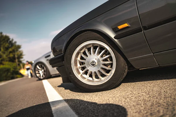 Rome, italy 10 september 2025: bmw e30 displaying vintage styling with its classic wheel, rim, and tire on an asphalt road experiencing strong sunlight