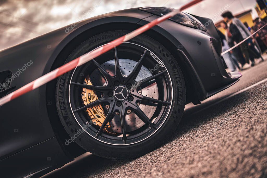 Rome, italy 10 september 2025: matte black mercedes-amg gt wheel with gold brake caliper close-up at automotive event on asphalt, high-performance detail shot