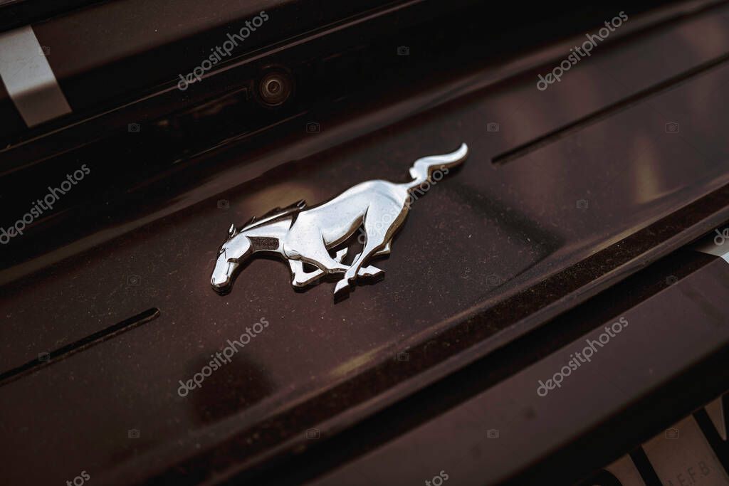 Rome, italy 10 september 2025: ford mustang running horse emblem in chrome on a dark vintage car body, symbolizing power, speed and automotive heritage