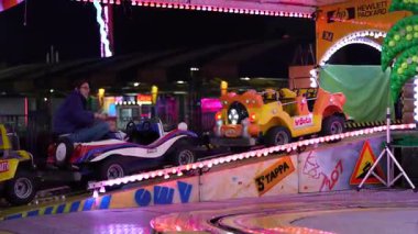 Roma, İtalya, 27 Ekim 2025: Mutlu anne ve küçük çocuğu eğlence parkında aydınlık bir araba atlıkarıncasında eğleniyorlar.