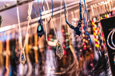 Karmaşık düğümler ve doğal boncuklarla donatılmış dekoratif makrome kolyeler bir market tezgahında asılı bohem el yapımı mücevherler zanaatkar tekstil ve renkli stil sergileniyor.