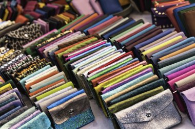 Değişik desenler, desenler ve malzemeler sergilenen renkli küçük çantalar ve cüzdanlar koleksiyonu, moda aksesuarları alışverişi için cazip bir görüntü yaratıyor.