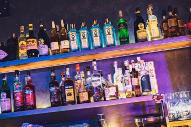 Este, İtalya 28 Ekim 2025: çeşitli alkol şişeleriyle dolu bar rafları, bir gece kulübünde farklı içki ve içki markaları sergileniyor.