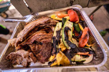 Alüminyum folyoyla kaplanmış ızgara domuz eti, tavuk, kabak ve dolma biber. Arkadaşları ve ailesiyle birlikte açık hava barbekü partisinde servis yapmaya hazır.
