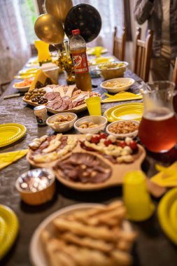 Milan, İtalya, 28 Ekim 2025: Aperatifler, şarküteri, atıştırmalıklar ve içeceklerle dolu şenlikli yemek masası eğlenceli bir kapalı mekan kutlaması ya da toplanma için hazır.