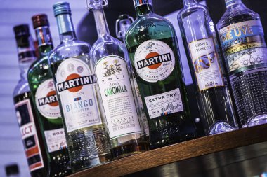 Milan, İtalya, 28 Ekim 2025: ahşap bir bar rafında İtalyan likörü ve vermut şişeleri kuyruğu, özel seçim kokteyller ve aperatifler için hazır, yakın çekim manzarası