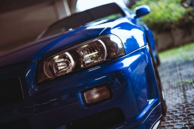 Milan, İtalya 28 Ekim 2025: Nissan Skyline gt-r r34 ön manzara ikonik farları vurguluyor, tampon ve parlak mavi vücut ışığı yansıtıyor