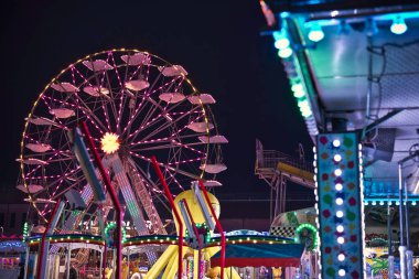 Milan, İtalya 27 Ekim 2025: Parlak dönme dolap ve renkli karnaval ışıkları ailelerin ve çiftlerin gezintilerin ve şenlikli eğlencenin keyfini çıkarırken gece gökyüzünü canlandırıyor.