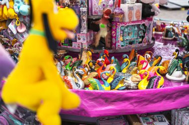 Milan, İtalya, 27 Ekim 2025: farklı renklerde dekoratif kuğu heykelcikleri bir market tezgahında sergileniyor, diğer çizgi film karakterleri arasında dikkat çekiyor.