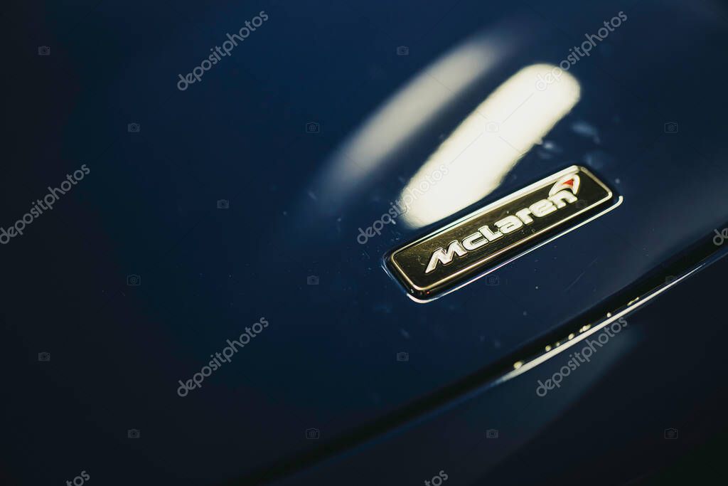 Milan, italy 28 october 2025: mclaren logo emblem close-up on glossy dark blue sports car hood, metallic chrome detail highlighting luxury, speed and precision engineering